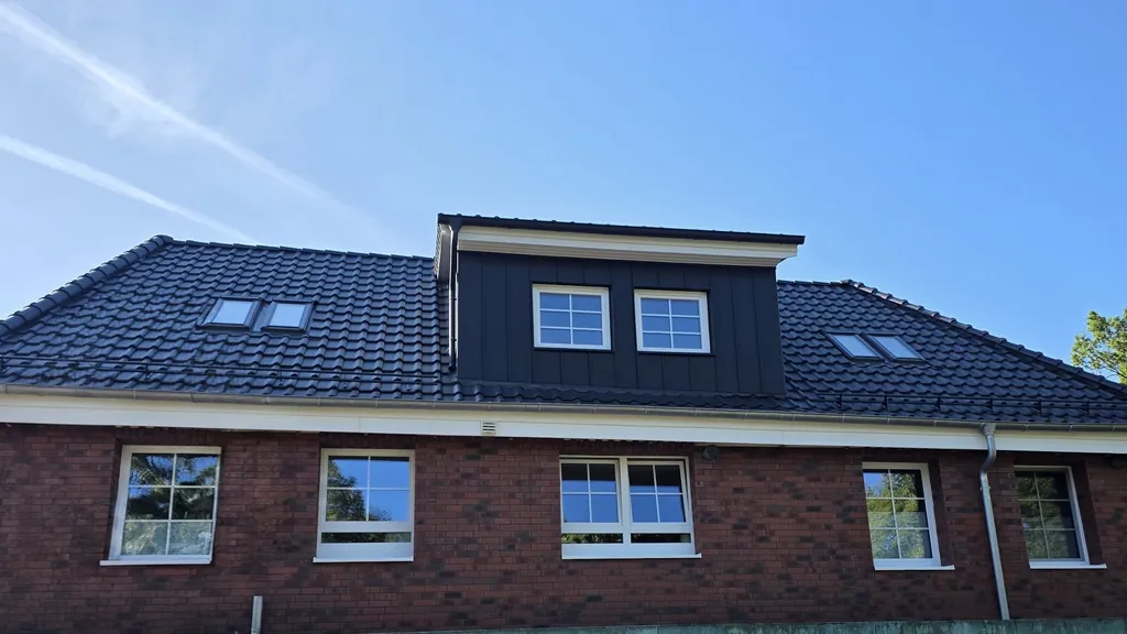 Klinkerhaus mit neuem anthrazitfarbenem Dach und großer Gaube in Stehfalz