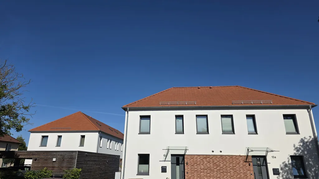 Wohnhaus mit rotem Walmdach, weißer Fassade und Schneefanggittern