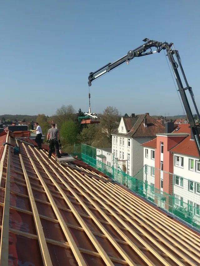 Dachdecker richtet Firstpfannen auf einem Steildach aus